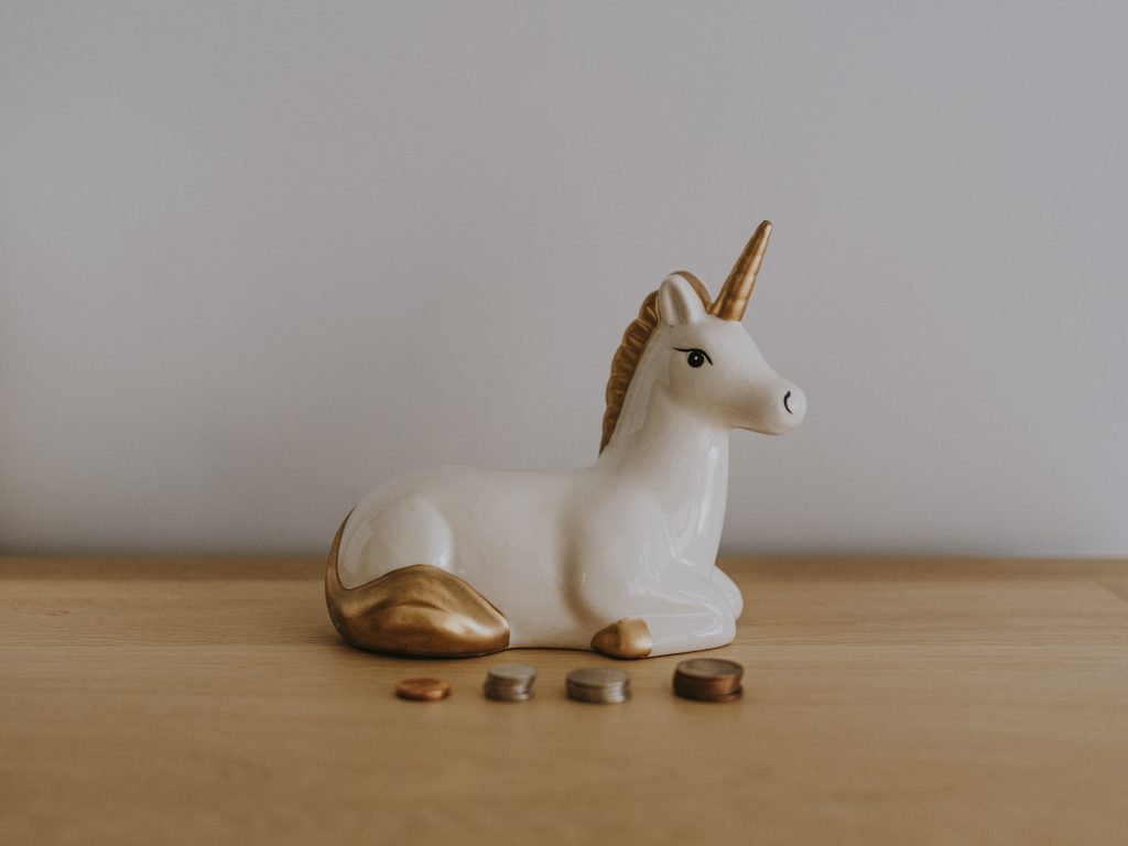 unicorn money box on a desk with coins