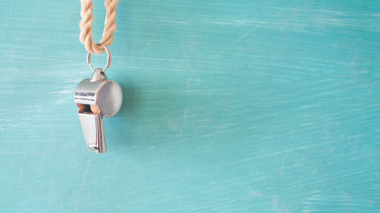 A whistle hanging on a light blue wall