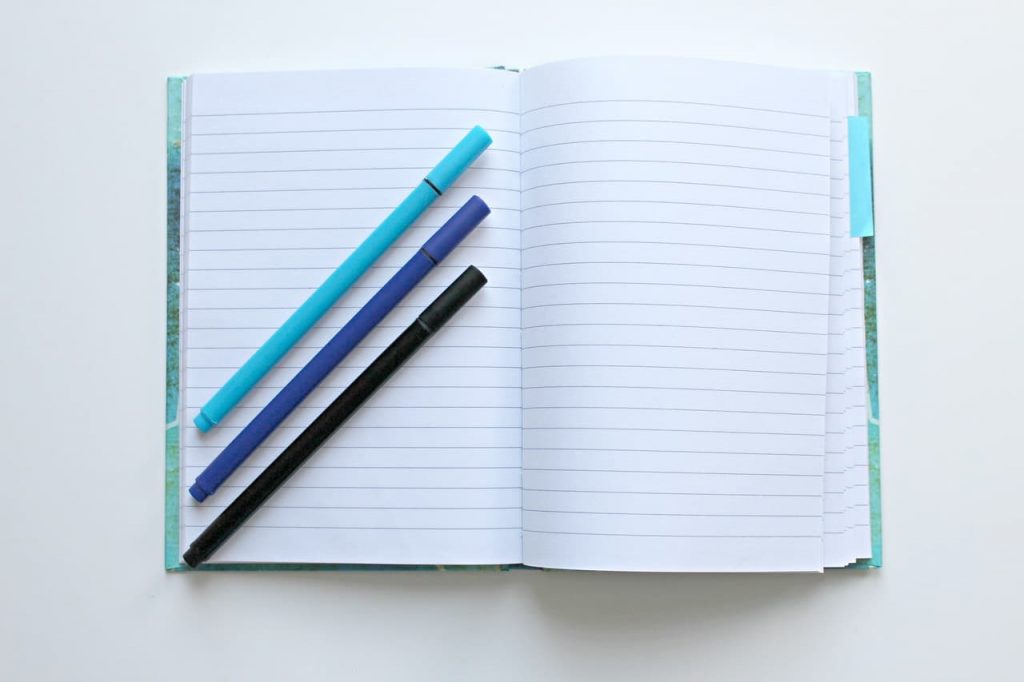 blue notebook with pens on a table