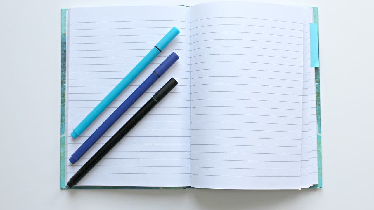 blue notebook with pens on a table